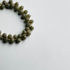 Green beaded bracelet on a light gray background