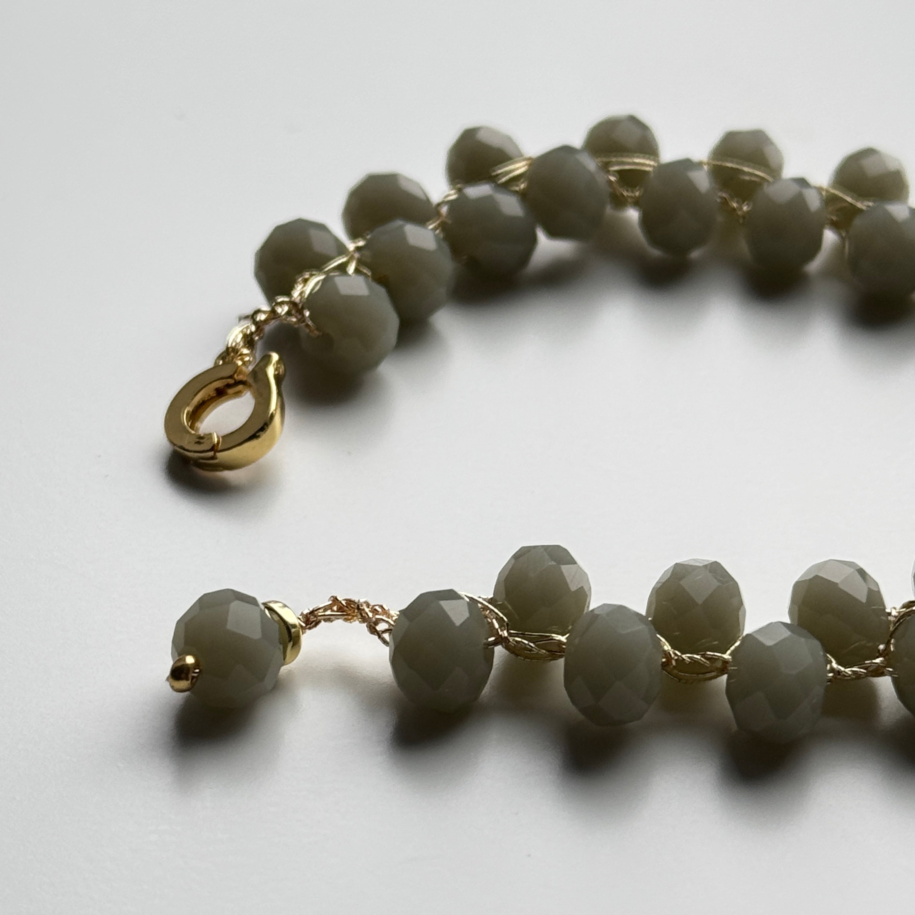 Bracelet with gray beads and gold accents on a light background