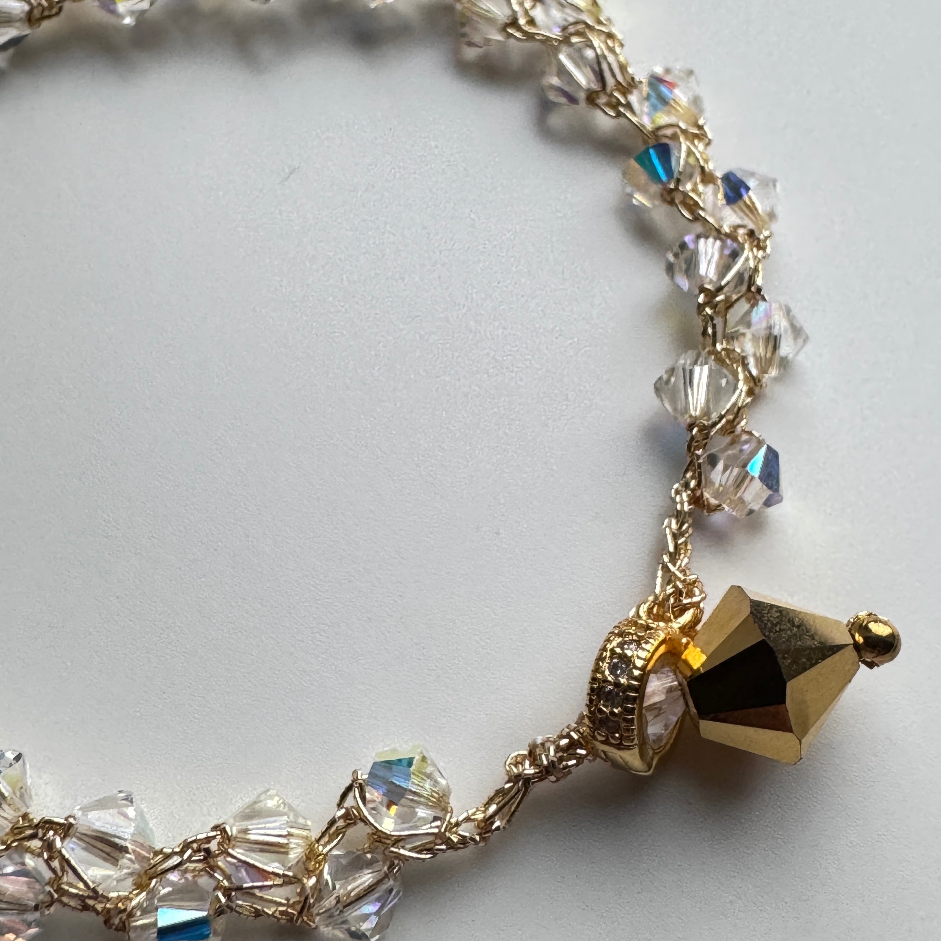 Gold bracelet with crystal beads on a light gray background
