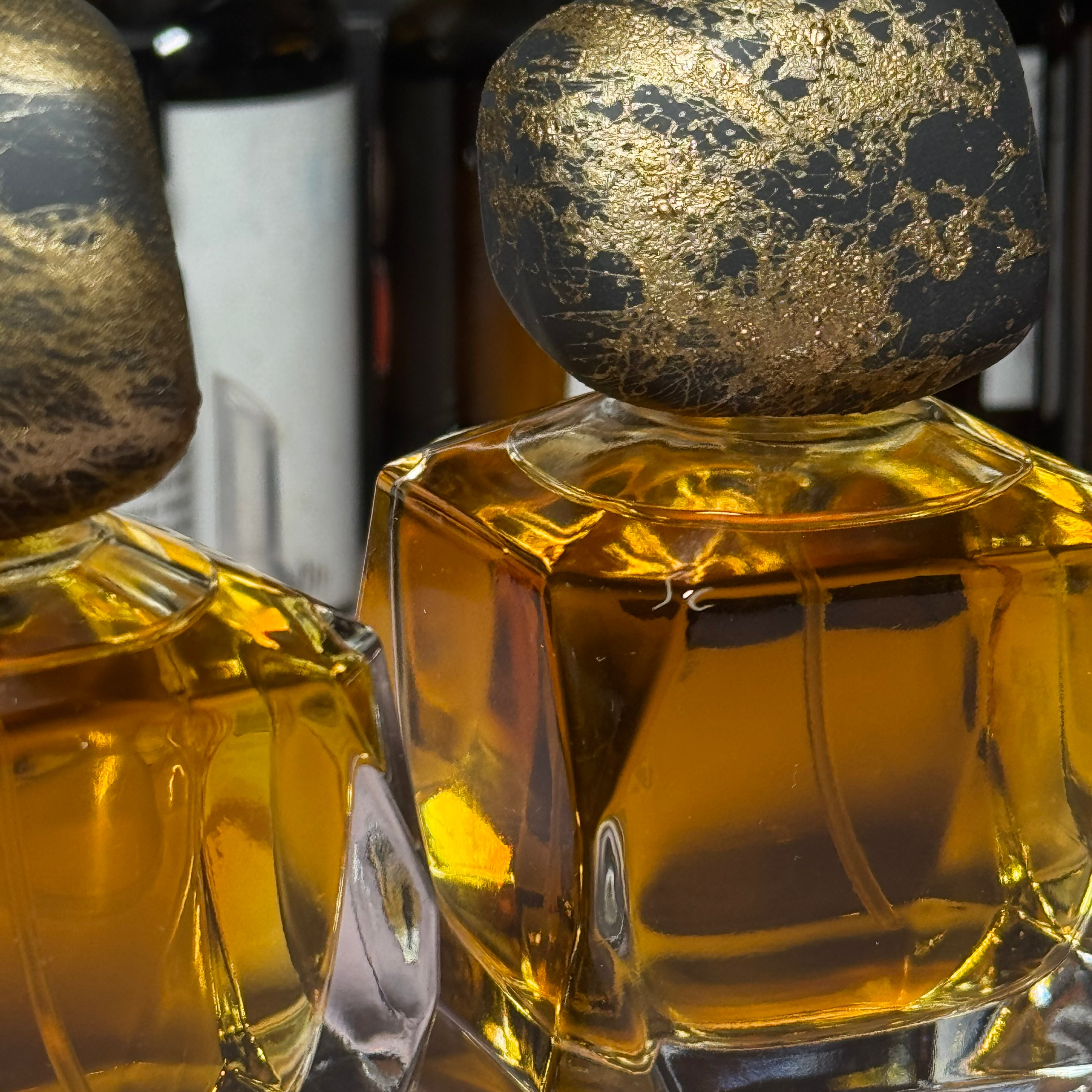 Two perfume bottles with gold caps on a reflective surface