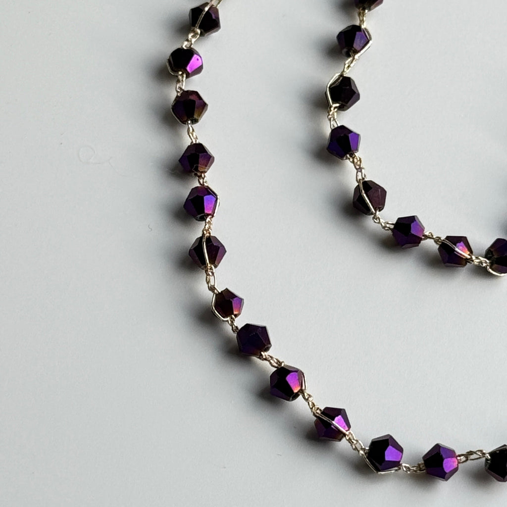 Necklace with purple beads on a light gray background