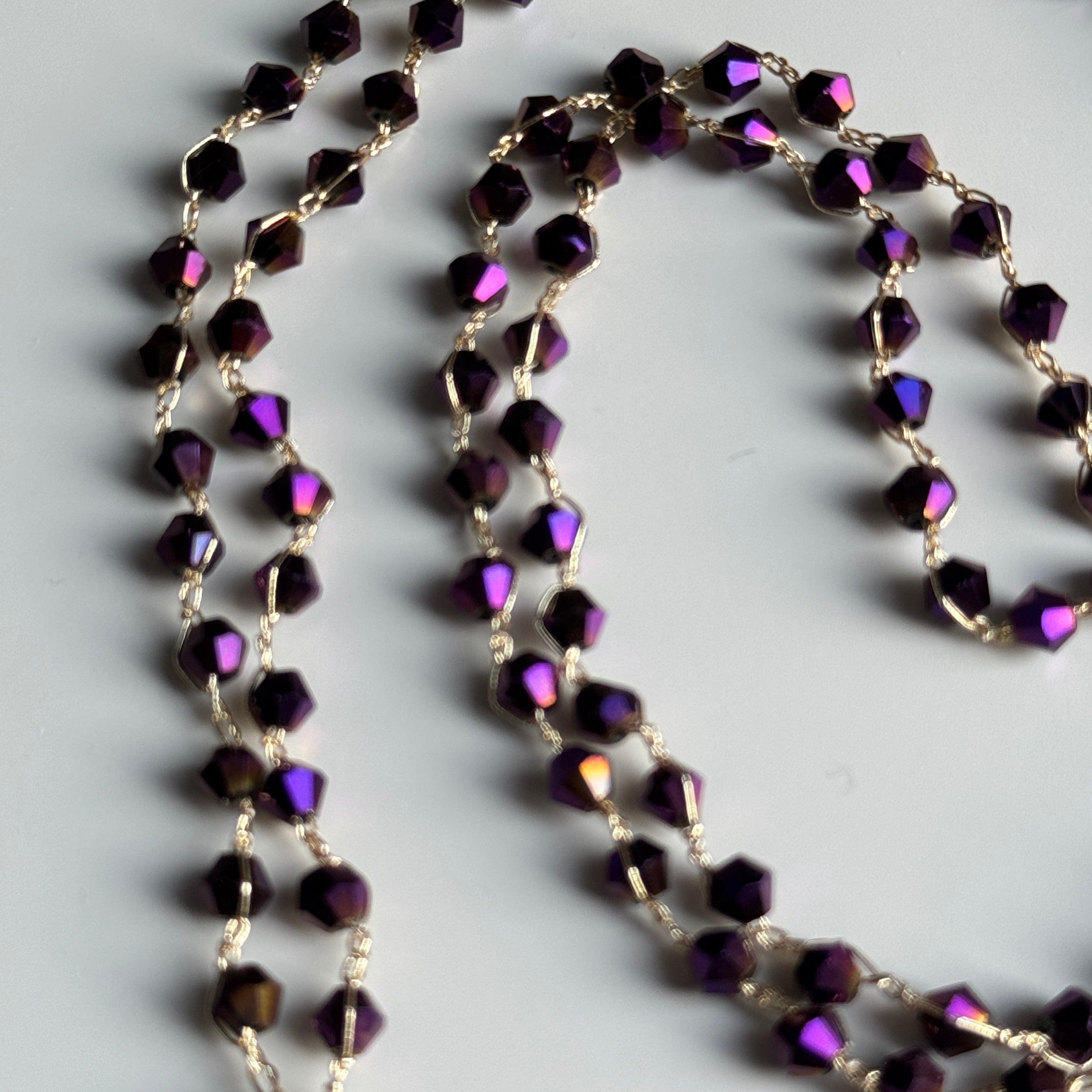 Purple beaded necklace on a light gray background