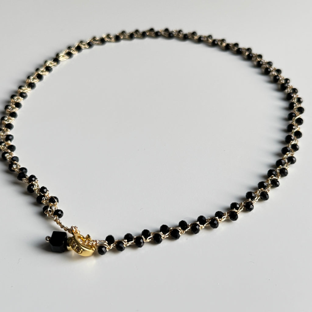 Rankų darbo nerats auksinio atspalvio kaklo papuošalas su juodais stiklo karoliukais