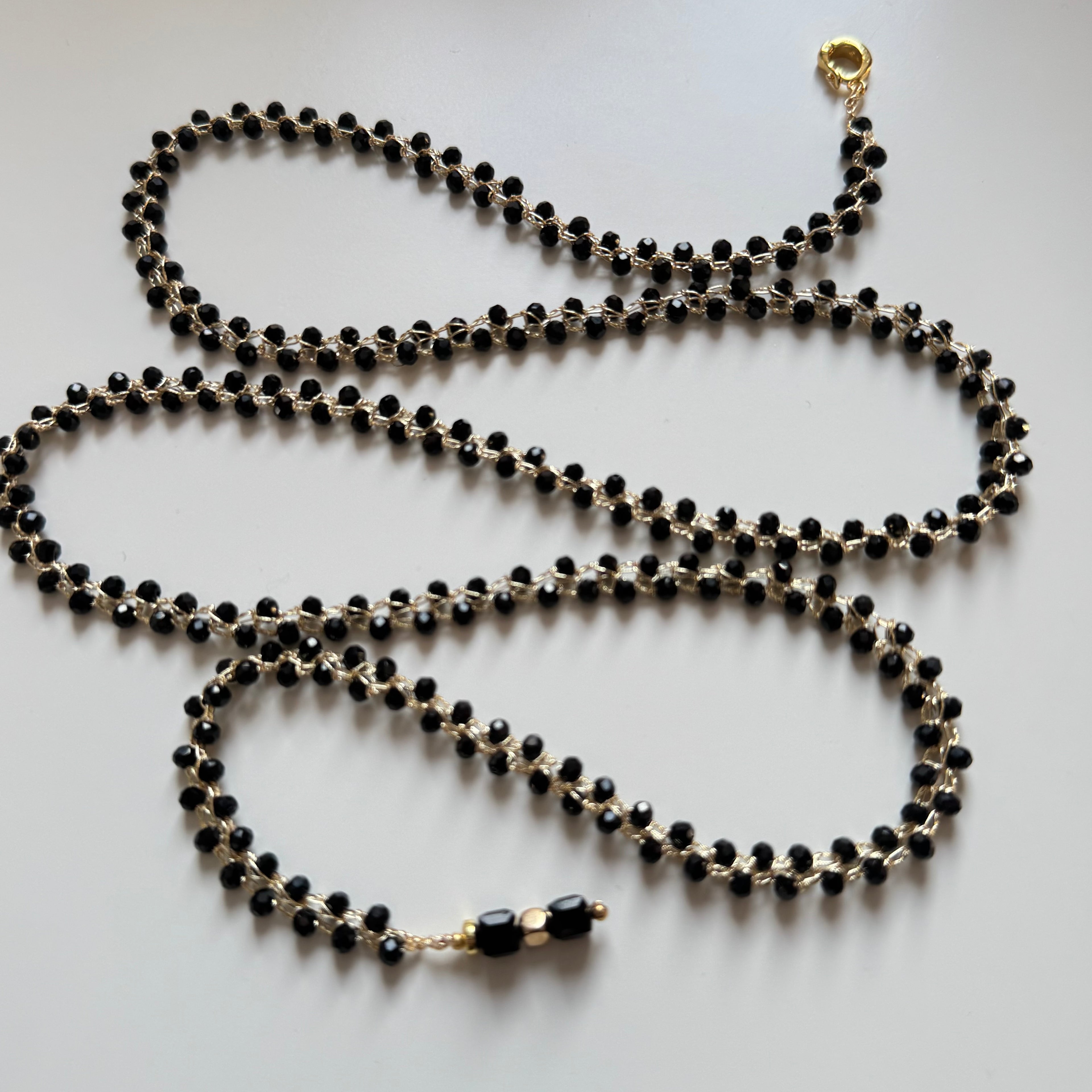 labai ilgas universalus kaklo papuošalas su juodos spalvos kristalais