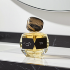 Kvepalų buteliukas su užrašu mood'or perfumes, pastatytas ant atspindinčio paviršiaus, su neryškiu fonu