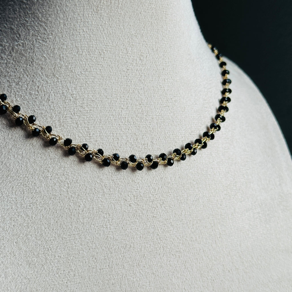 nertas vėrinys atrodo kaip grandinėlė su juodais smulkiais stiklo kristalais ant stovo