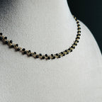 nertas vėrinys atrodo kaip grandinėlė su juodais smulkiais stiklo kristalais ant stovo