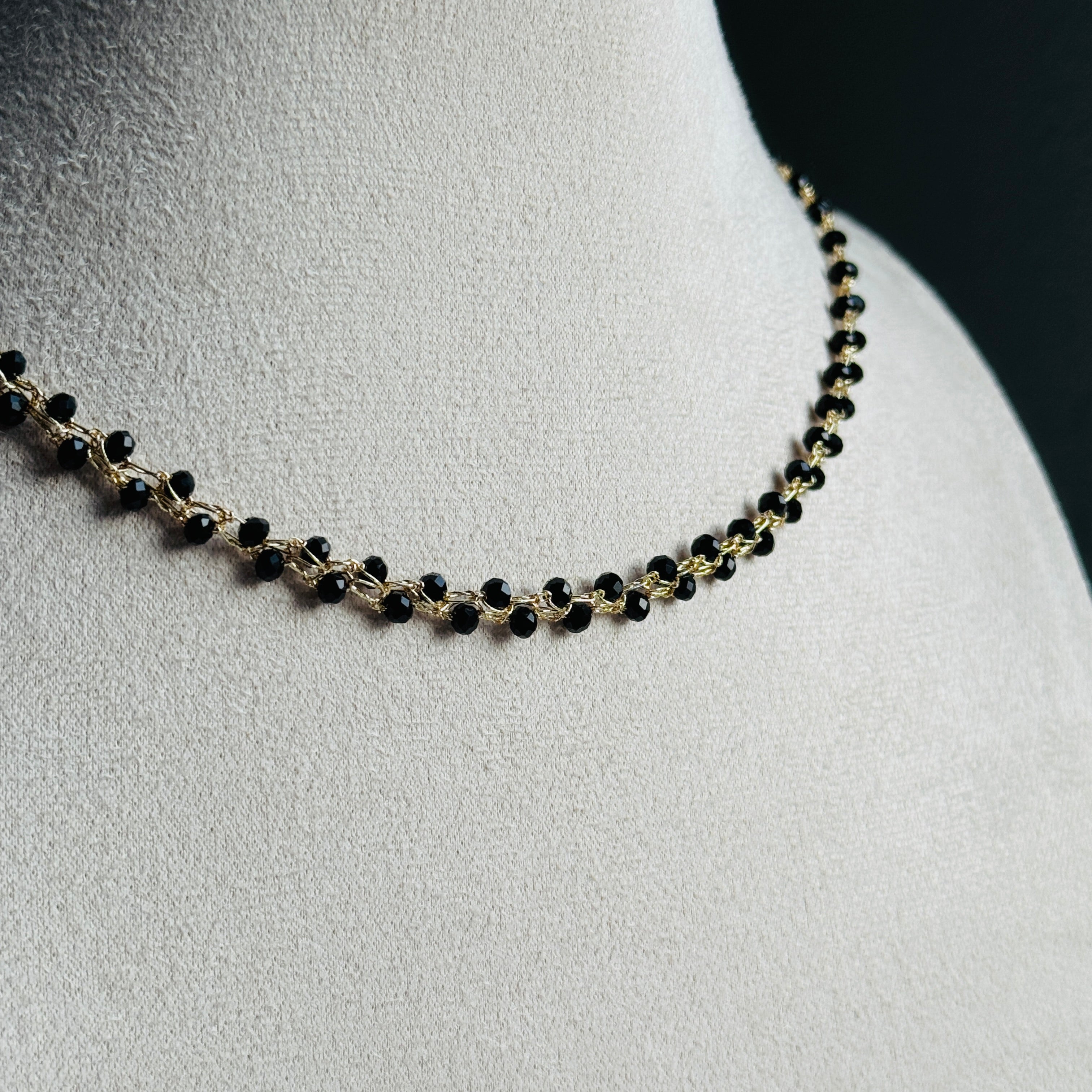 nertas vėrinys atrodo kaip grandinėlė su juodais smulkiais stiklo kristalais ant stovo