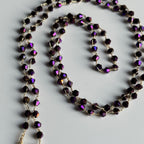 Necklace with purple bicone glass beads on a light gray background