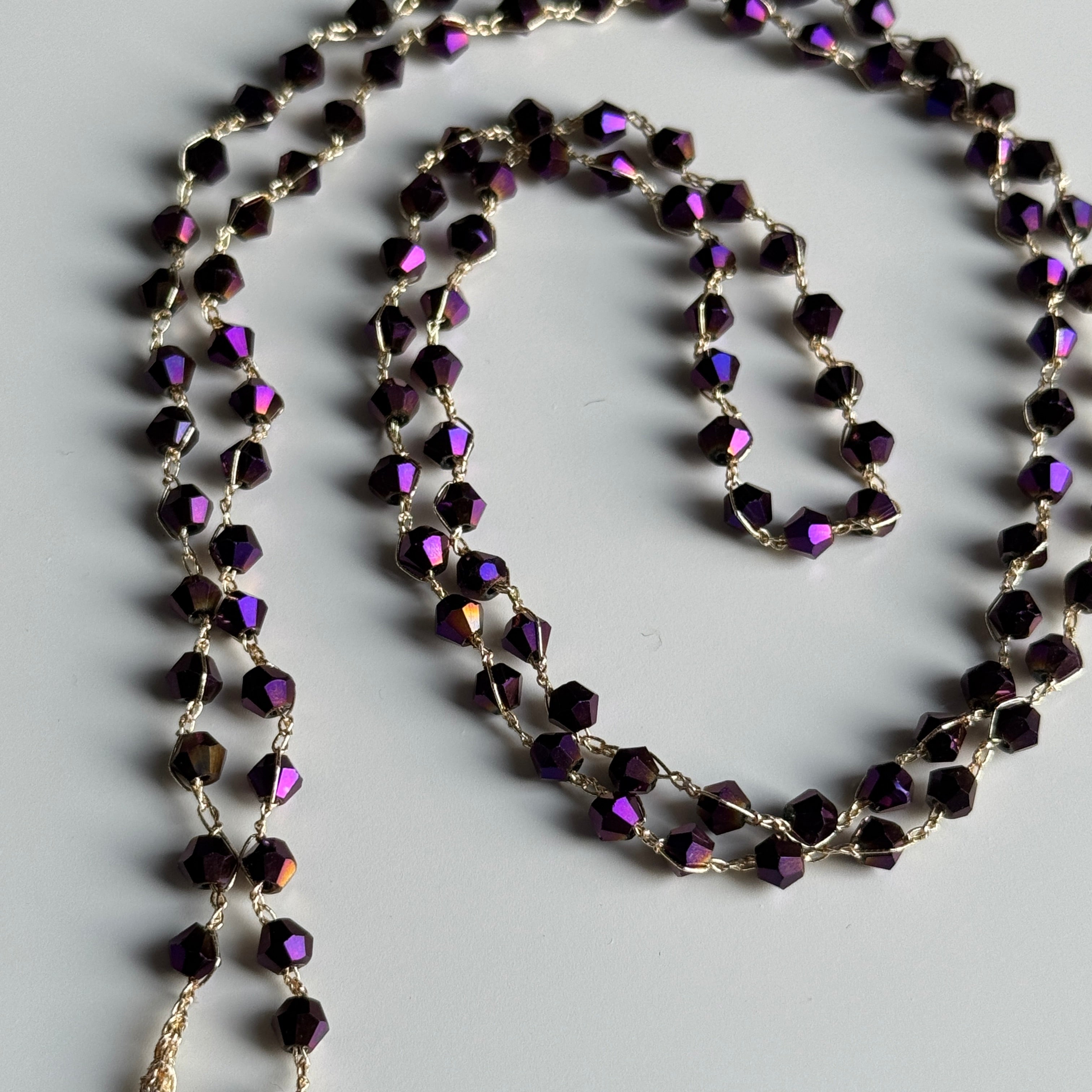 Necklace with purple bicone glass beads on a light gray background