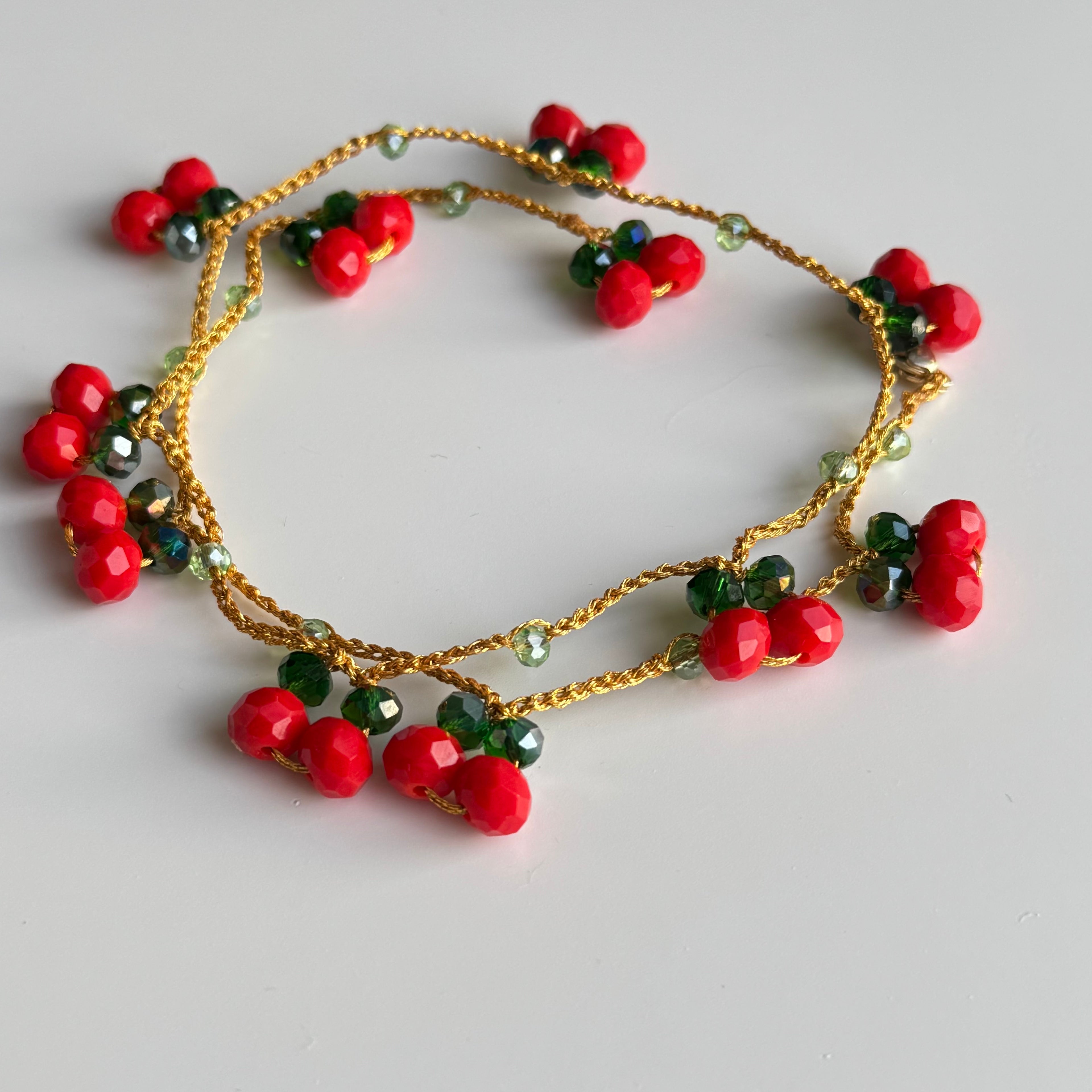 raudonų karoliukų apyrankė nunerta iš metalizuotų siūų ir raudonų bei žalių stiklo kristalų