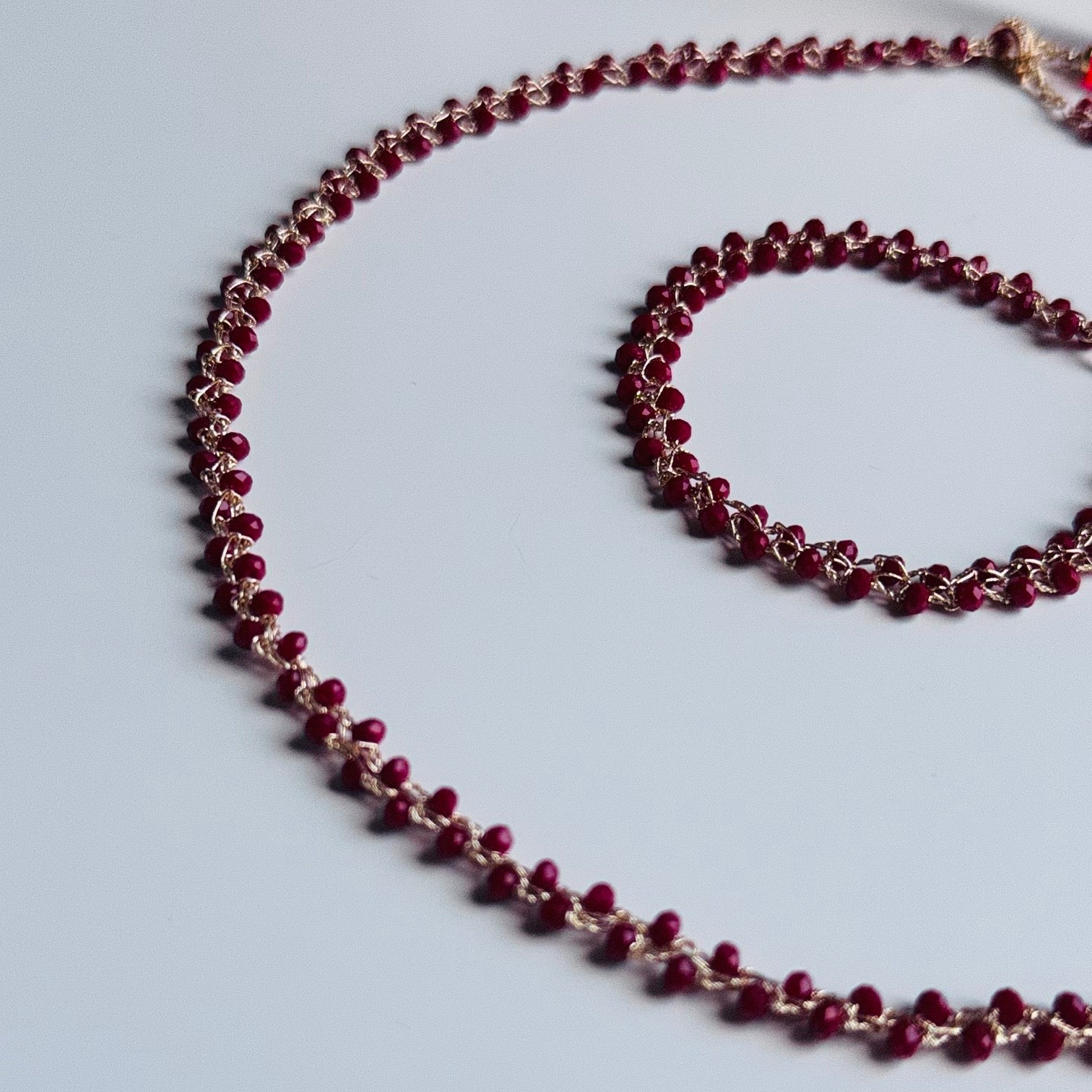 Raudonų karoliukų kaklo vėrinys ir apyrankė auksinio atspalvio sidabru dengtas siūlas