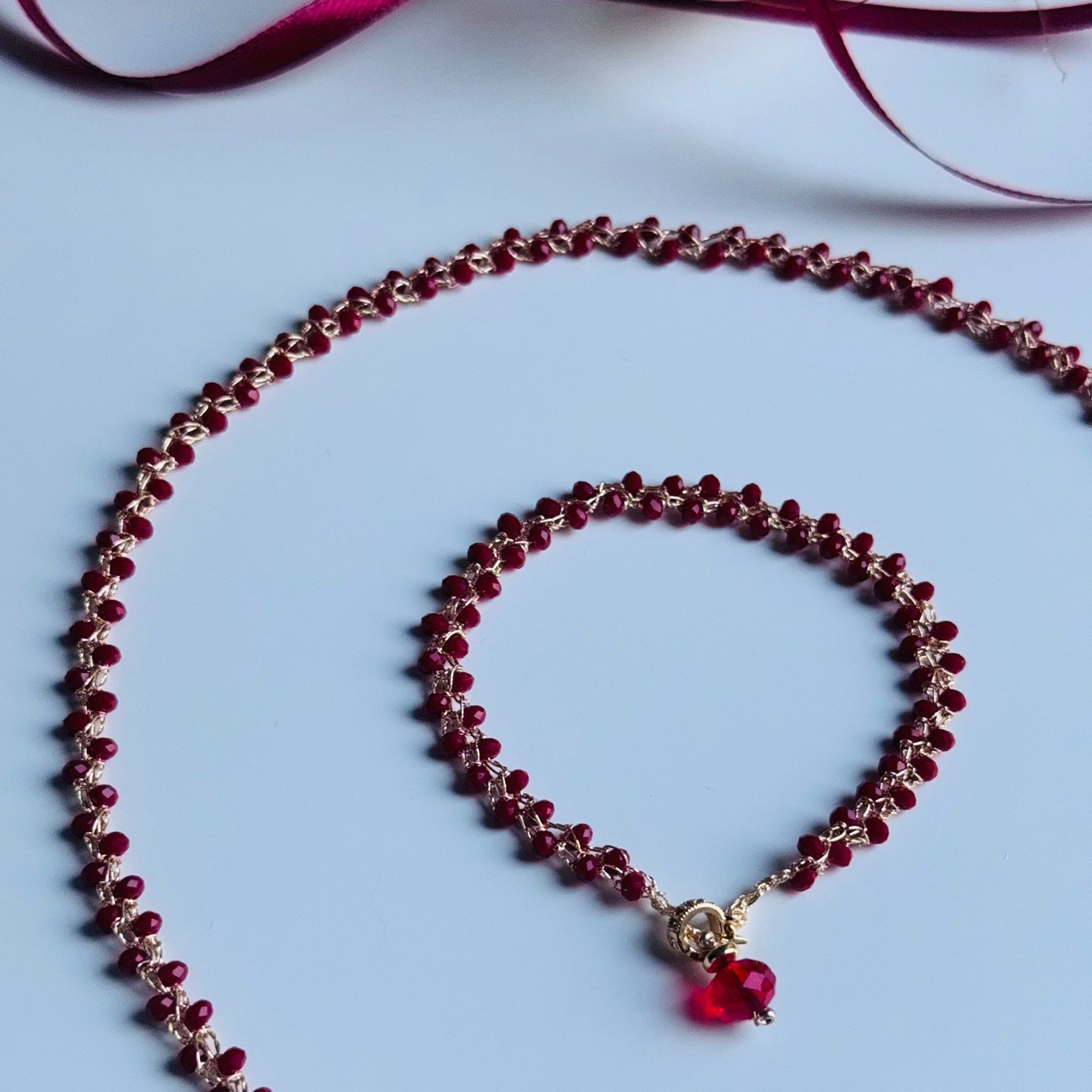 Rankų darbo auksinio atspalvio grandinėlė nunerta su smulkiais raudonais karoliukais, prabangus papuošalų komplektas